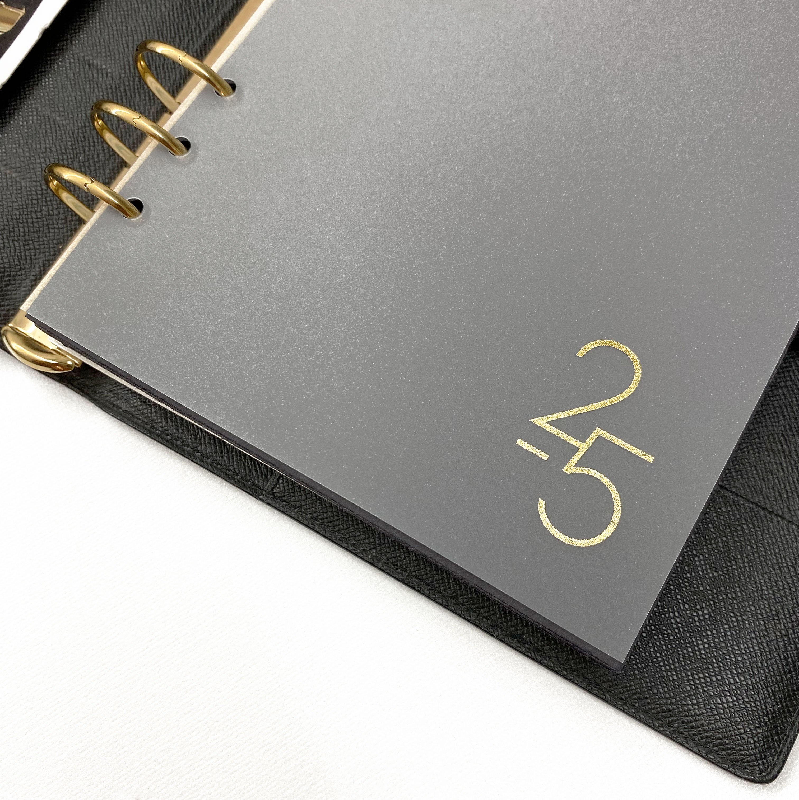 Gold foiled planner dashboard inside a luxury A5 6 ring Louis Vuitton GM agenda shown in black epi leather.